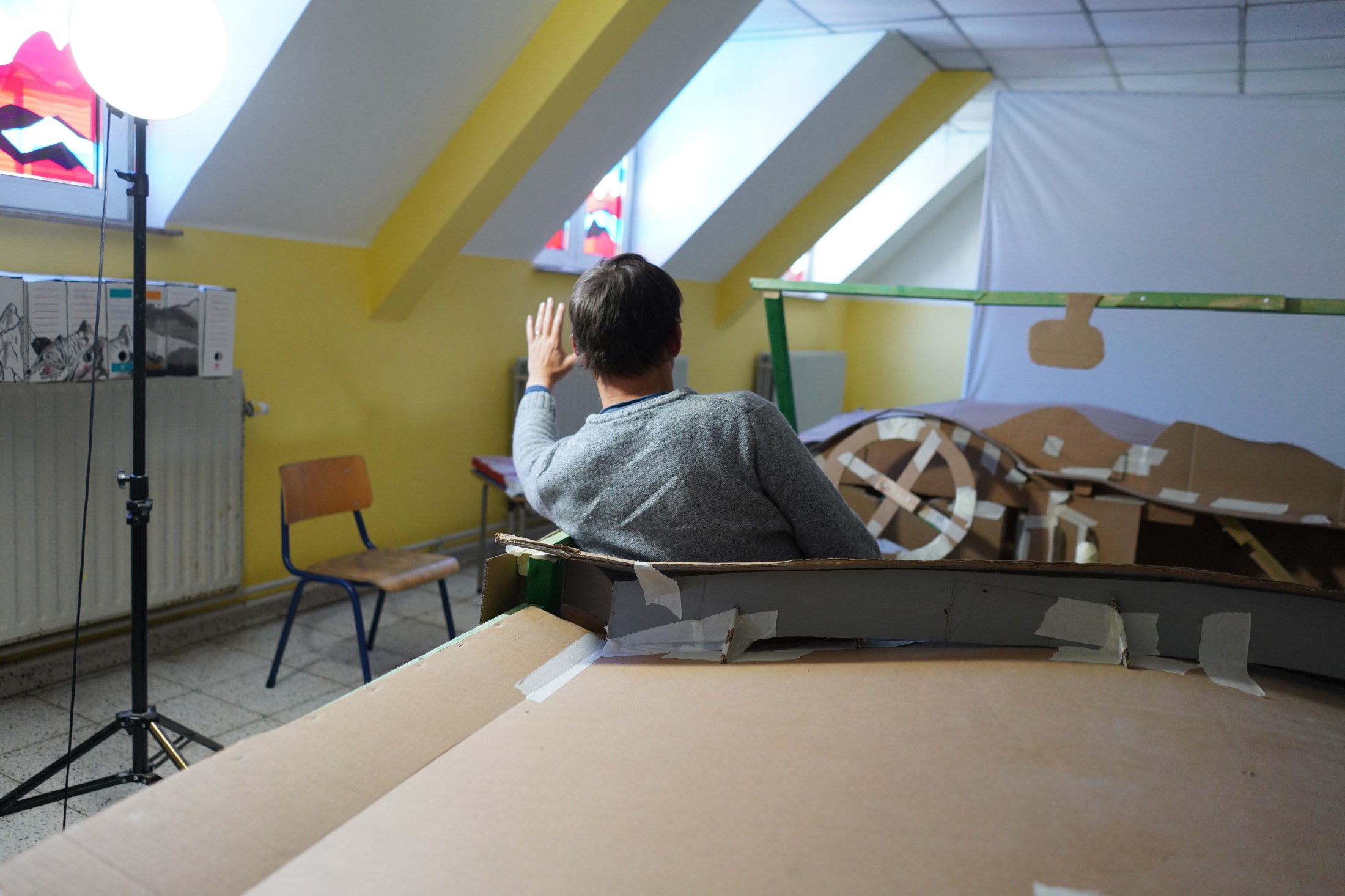 Photograph of Jan Verbruggen seated in his handmade cardboard car, inspired by a Mercedes cabriolet, which serves as a model for the painting The Night Journey, currently still in progress, 2026.